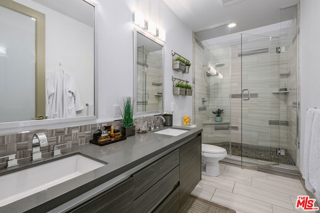 bathroom with backsplash, vanity, an enclosed shower, and toilet