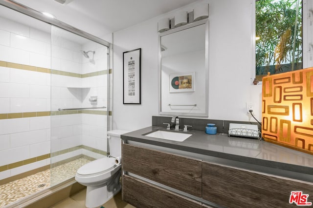 bathroom featuring vanity, toilet, and a shower with door