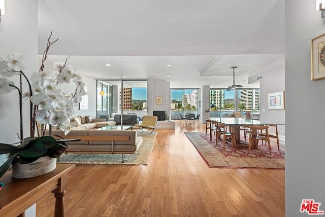 living room featuring floor to ceiling windows, light wood-type flooring, and a wealth of natural light