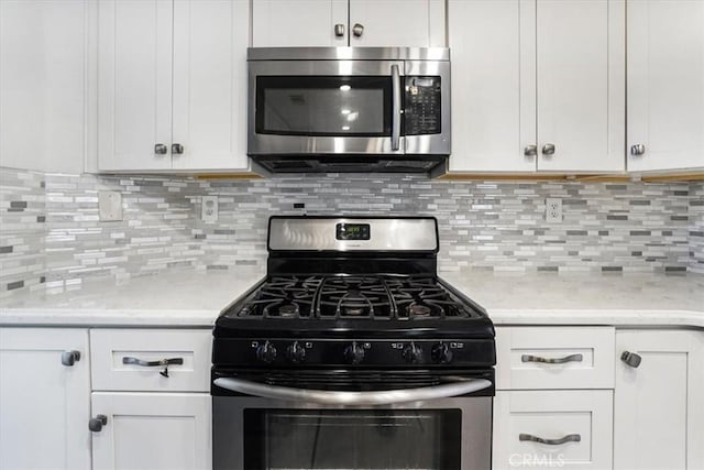 kitchen featuring decorative backsplash, white cabinets, appliances with stainless steel finishes, and light stone countertops