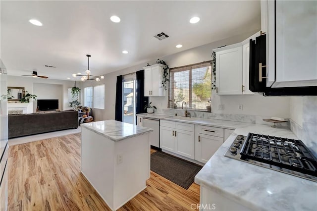 kitchen with dishwasher, a kitchen island, white cabinetry, and ceiling fan with notable chandelier