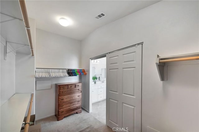 spacious closet featuring light colored carpet and vaulted ceiling