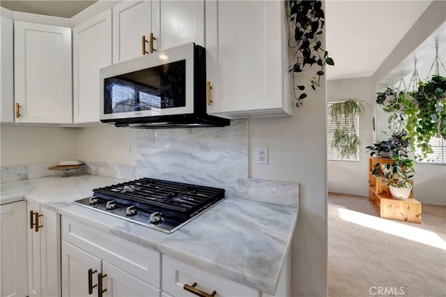 kitchen featuring backsplash, light carpet, white cabinets, light stone countertops, and appliances with stainless steel finishes