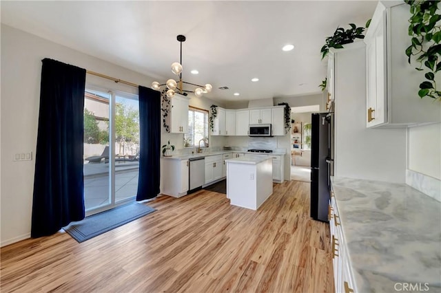 kitchen featuring a center island, white cabinetry, stainless steel appliances, and light hardwood / wood-style flooring