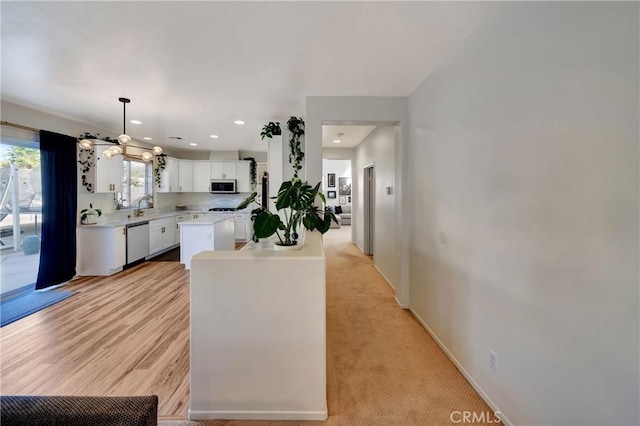 kitchen with a center island, white cabinets, sink, hanging light fixtures, and stainless steel appliances