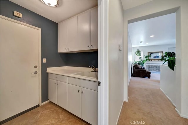 laundry area featuring light carpet and sink