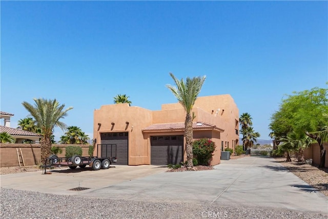 adobe home featuring central AC unit and a garage