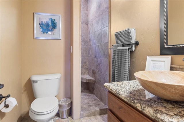 bathroom with vanity, toilet, and tiled shower