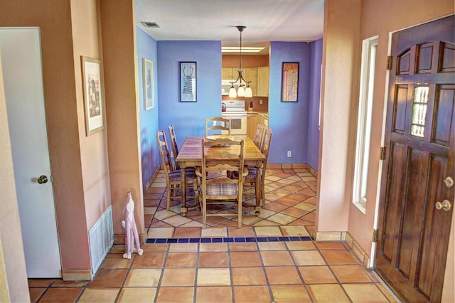 tiled dining room featuring an inviting chandelier