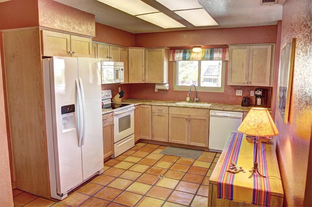 kitchen with light brown cabinets, white appliances, sink, and light tile patterned floors