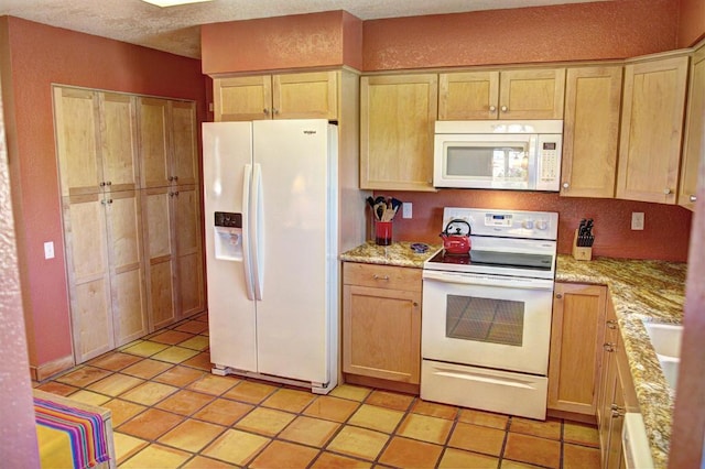 kitchen featuring light stone countertops, light brown cabinets, light tile patterned floors, and white appliances