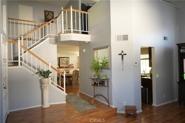 entrance foyer featuring a towering ceiling and dark wood-type flooring