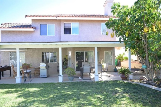 rear view of property featuring a lawn and a patio area