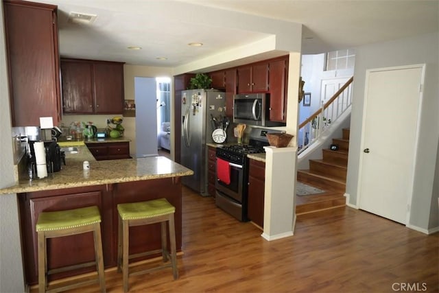 kitchen featuring kitchen peninsula, stainless steel appliances, and dark hardwood / wood-style floors