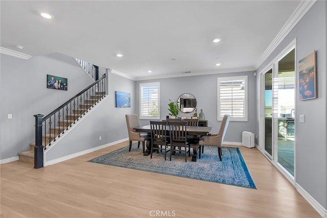 dining space with light hardwood / wood-style flooring, a healthy amount of sunlight, and ornamental molding