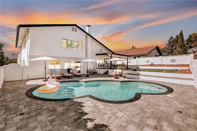 pool at dusk with a patio