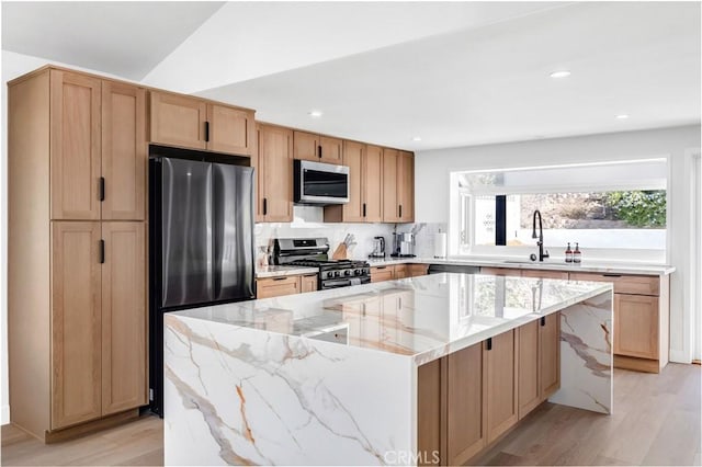 kitchen with sink, a kitchen island, stainless steel appliances, and light hardwood / wood-style flooring