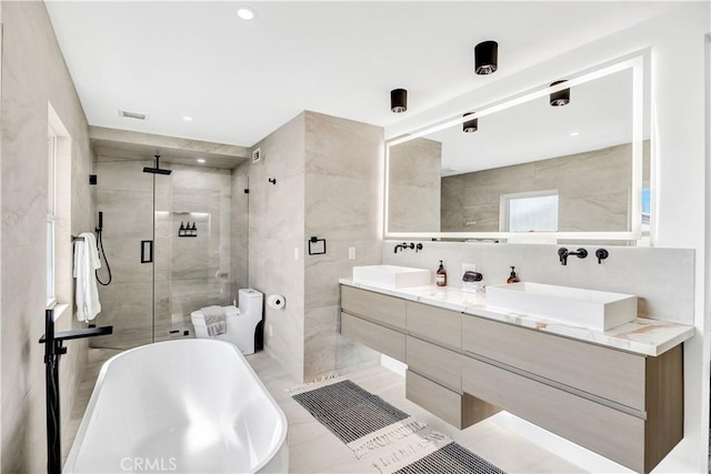 bathroom featuring tile patterned flooring, vanity, separate shower and tub, and tile walls