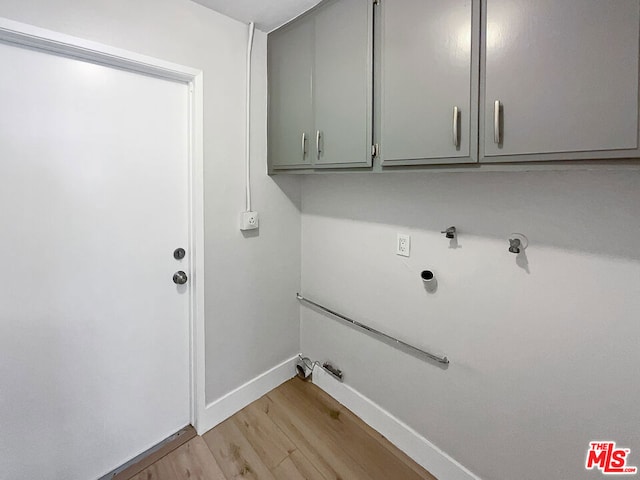 laundry room featuring gas dryer hookup, cabinets, and light wood-type flooring