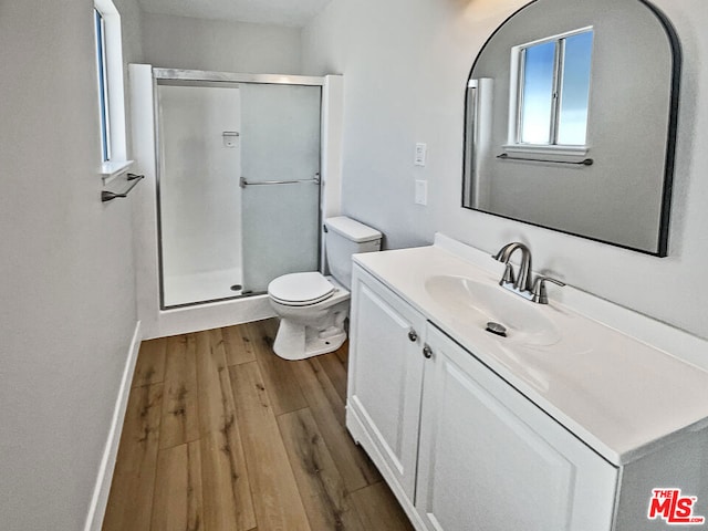 bathroom featuring vanity, hardwood / wood-style flooring, toilet, and a shower with shower door