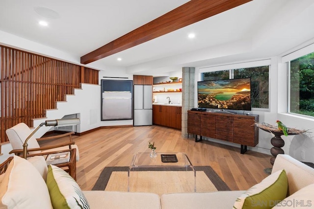 living room with beamed ceiling, light hardwood / wood-style floors, and sink