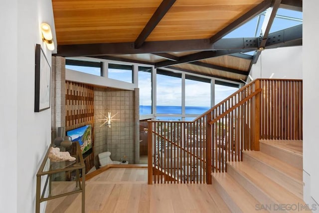 interior space with vaulted ceiling with beams, a water view, wooden ceiling, and hardwood / wood-style flooring