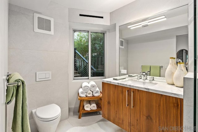 bathroom with tile patterned floors, vanity, toilet, and tile walls