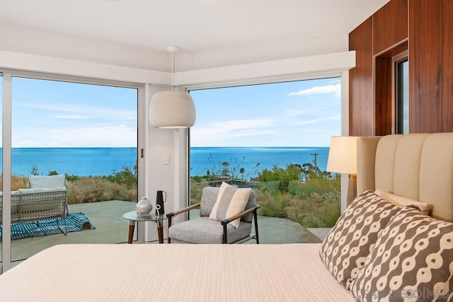 bedroom featuring multiple windows, wood walls, and a water view