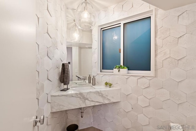 bathroom with decorative backsplash, sink, and tile walls