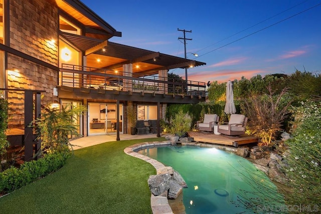 pool at dusk with a patio area and a lawn