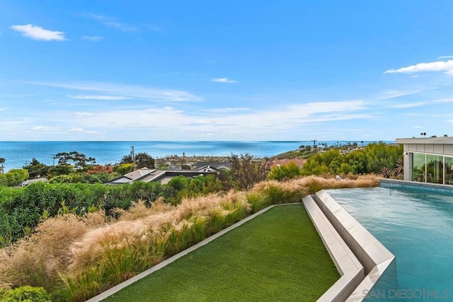 view of pool with a lawn and a water view