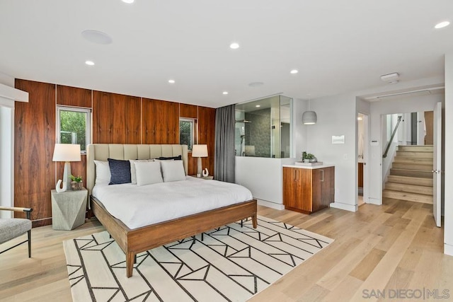 bedroom with wooden walls and light wood-type flooring