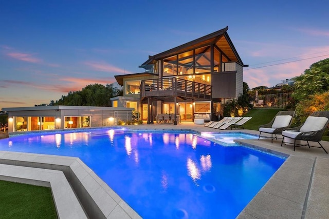 pool at dusk with a patio area and an in ground hot tub