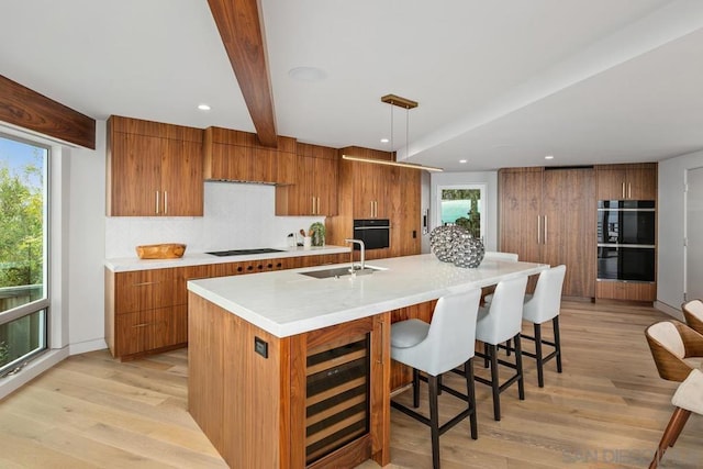 kitchen with a healthy amount of sunlight, hanging light fixtures, a large island, and sink