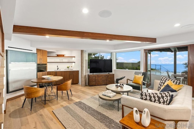 living room with light hardwood / wood-style flooring, beamed ceiling, and sink