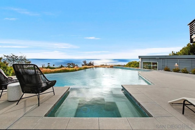 view of swimming pool with an in ground hot tub, a water view, and a patio area