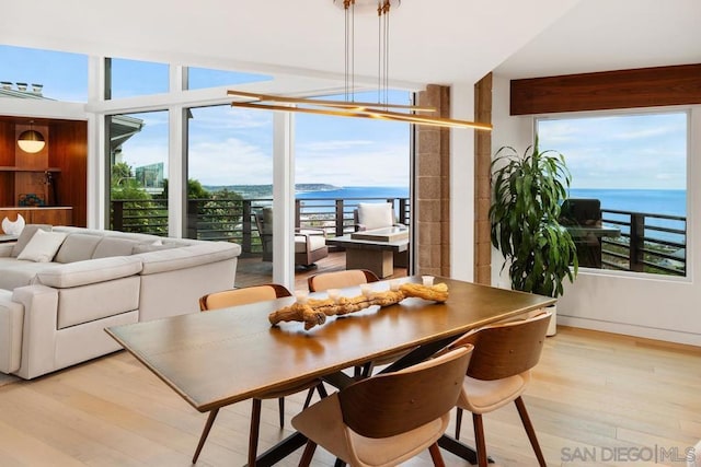 dining area featuring light wood-type flooring and a water view