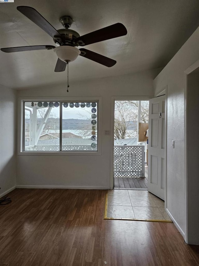 unfurnished sunroom featuring vaulted ceiling, plenty of natural light, and ceiling fan