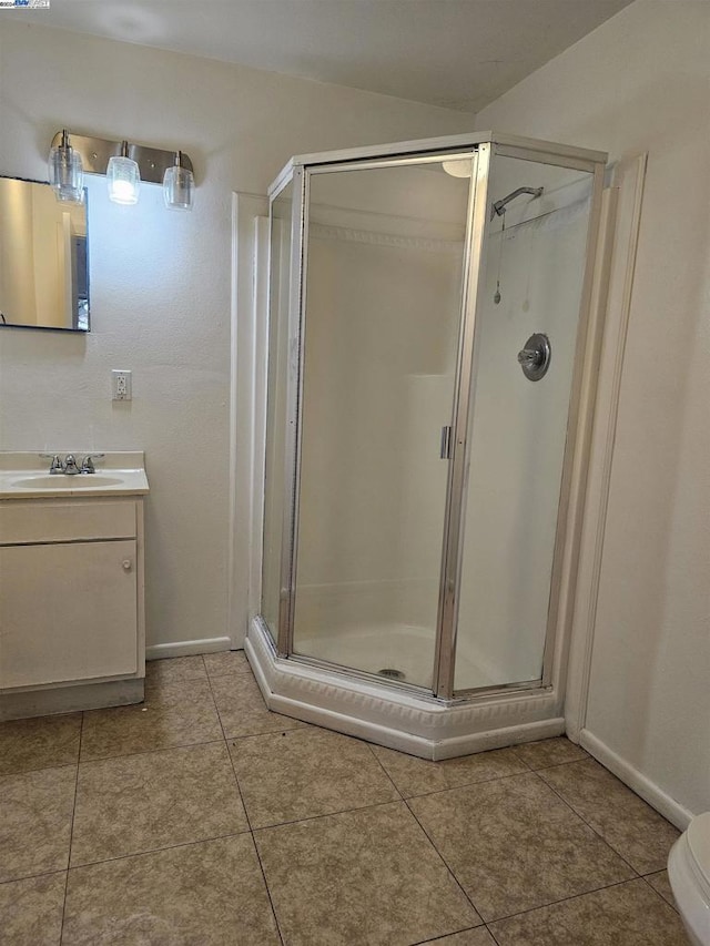 bathroom featuring tile patterned flooring, vanity, a shower with shower door, and toilet