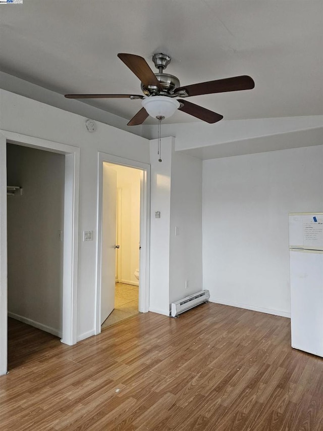 interior space with baseboard heating, ceiling fan, and light hardwood / wood-style flooring