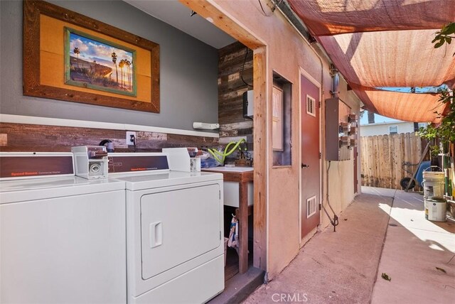 washroom with washer and dryer and wood walls