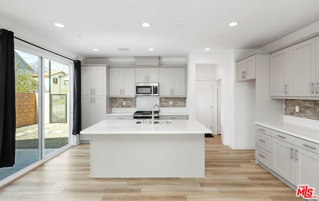 kitchen with sink, an island with sink, and light hardwood / wood-style flooring