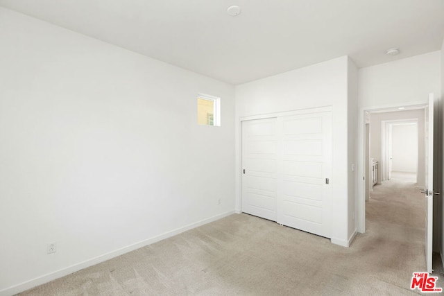 unfurnished bedroom featuring light carpet and a closet