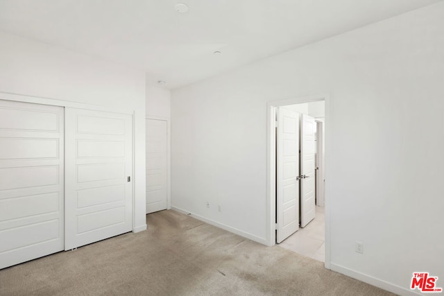 unfurnished bedroom with light carpet and a closet