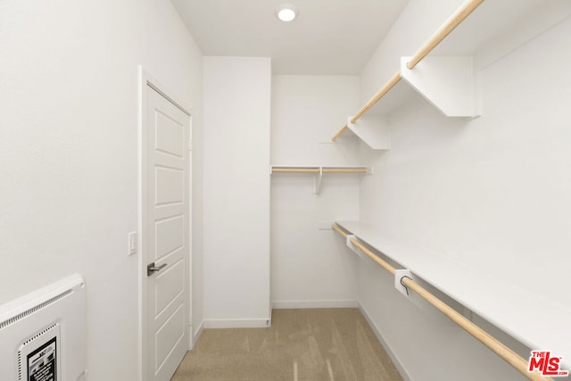 walk in closet featuring heating unit and light carpet