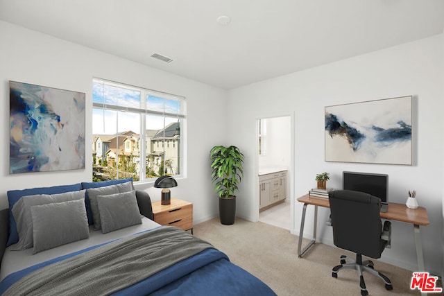 bedroom featuring connected bathroom and light colored carpet