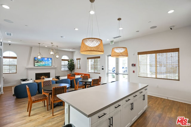 kitchen featuring a fireplace, decorative light fixtures, white cabinetry, and a wealth of natural light