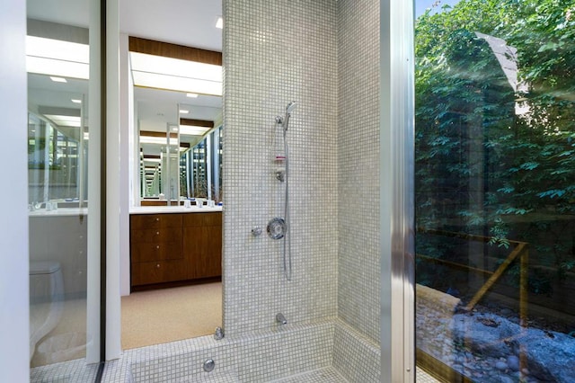 bathroom featuring a tile shower, vanity, toilet, and tile patterned floors