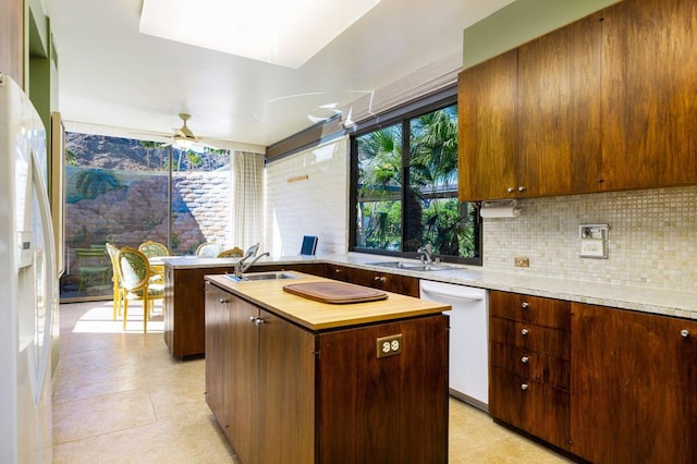 kitchen with ceiling fan, sink, an island with sink, and white appliances