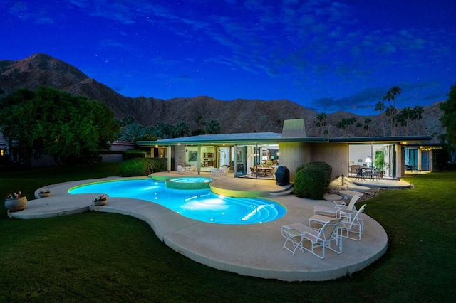 view of pool with a lawn, a mountain view, a patio area, and an in ground hot tub